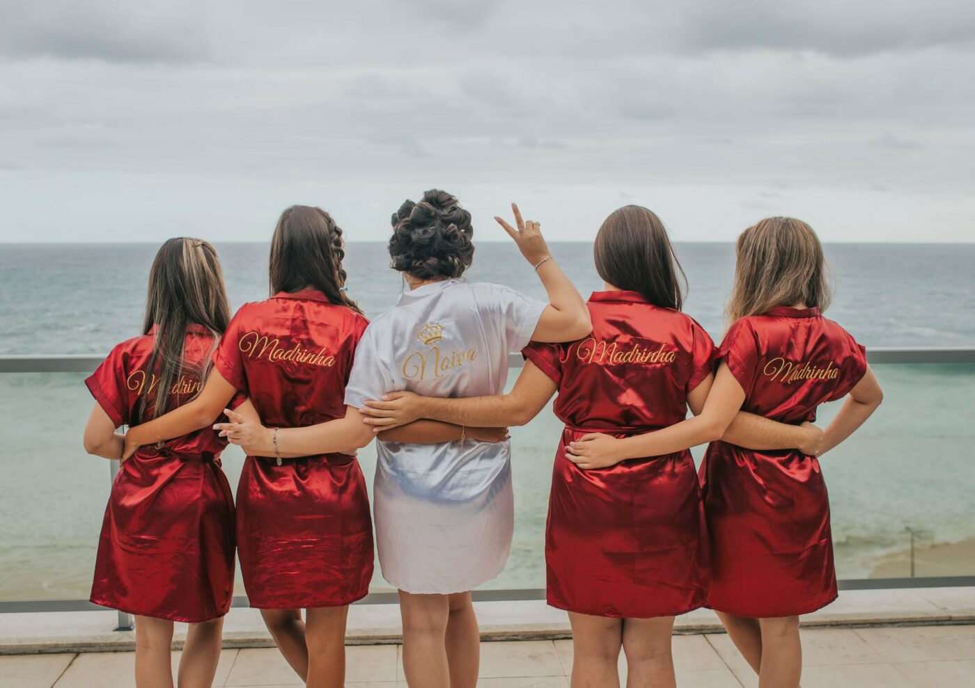 Four bridesmaids surrounding the bride in their custom pyjamas overlooking the ocean