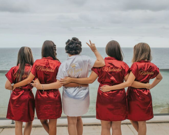 Four bridesmaids surrounding the bride in their custom pyjamas overlooking the ocean