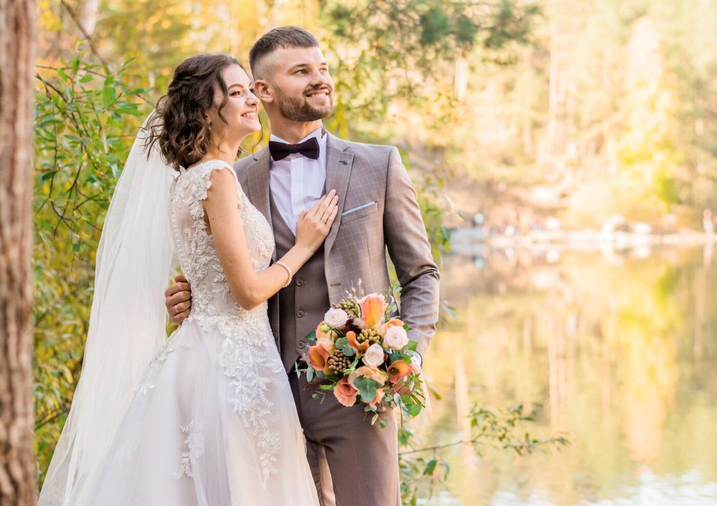 A newly married couple standing in front of a lake