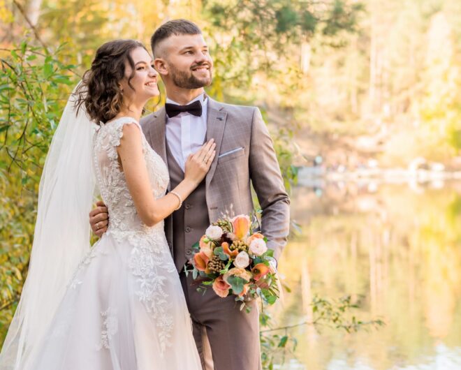 A newly married couple standing in front of a lake