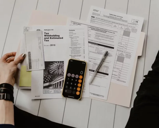 A women's hands sorting out invoices using the calculator on her phone