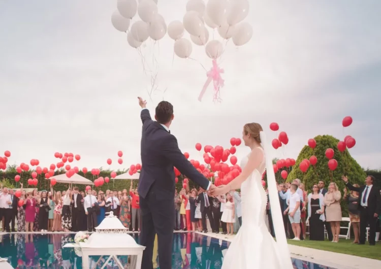 A newly married couple celebrating in front of their guests with balloons