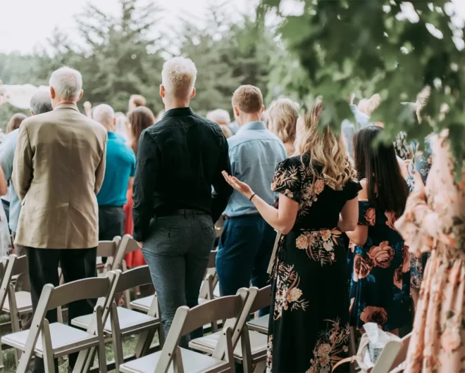 Guests standing in front of their chairs watching a wedding